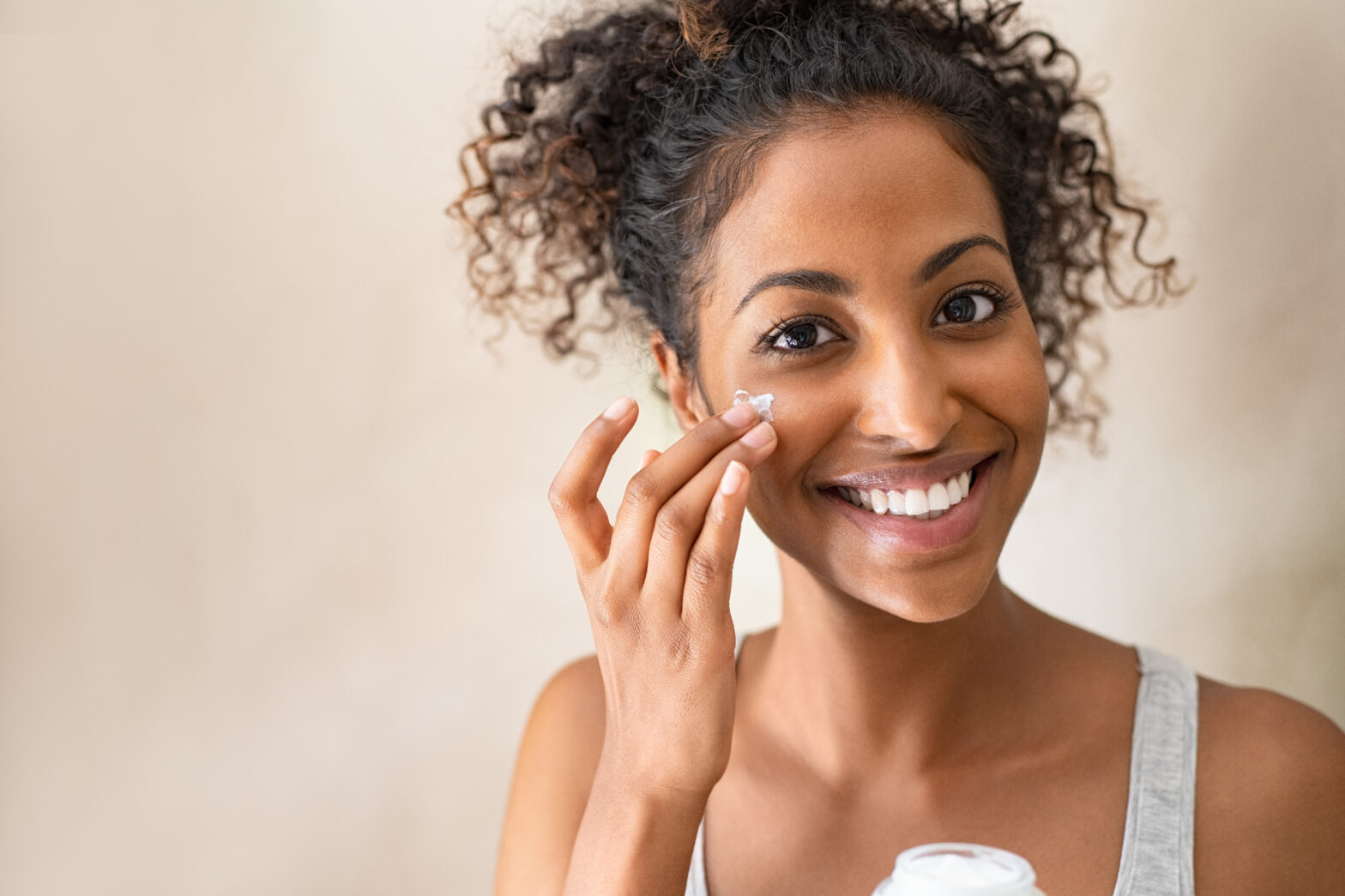 Smiling,African,Girl,With,Applying,Facial,Moisturizer,While,Holding,Jar